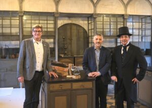 Die Umbauarbeiten im Liebig-Museum sind bis September 2025 veranschlagt. Prof. Dr. Gerd Hamscher, Vorsitzender der Justus Liebig-Gesellschaft (Mitte), und Matthias Funk, Technischer Vorstand der SWG (links), freuen sich darüber, dass das Gebäude künftig mit umweltschonender Fernwärme beheizt wird. Nach der Modernisierung kann Dr. Stephan Becker (rechts) seine spannende Experimentalvorlesung wieder an alter Stelle halten. Wegen des Brandes hat er die mobilen Experimente „Liebig to go“ entwickelt (Foto: Stadtwerke Gießen)